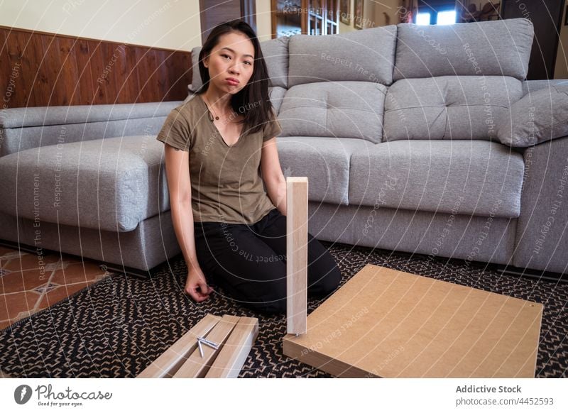 Asiatische Frau baut einen Tisch im Wohnzimmer zusammen versammeln achtsam Detailaufnahme diy Teppich Ornament Sofa heimwärts Raum Fokus Material Barfuß