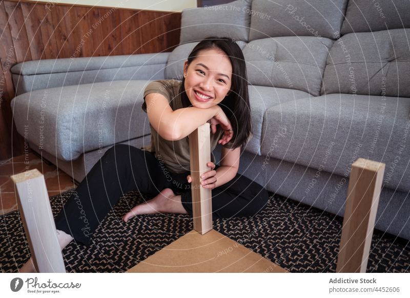 Asiatische Frau baut einen Tisch im Wohnzimmer zusammen versammeln achtsam Detailaufnahme diy Teppich Ornament Sofa heimwärts Raum Fokus Material Barfuß