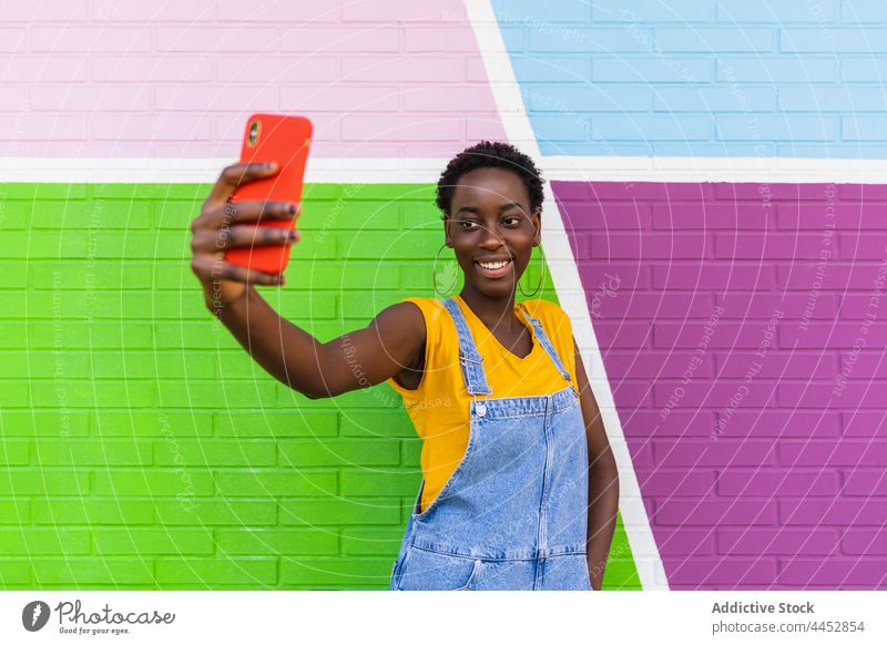 Lächelnde schwarze Frau, die ein Selfie mit ihrem Smartphone macht benutzend froh genießen farbenfroh einfangen Foto Bildschirm Gerät Glück Selbstportrait