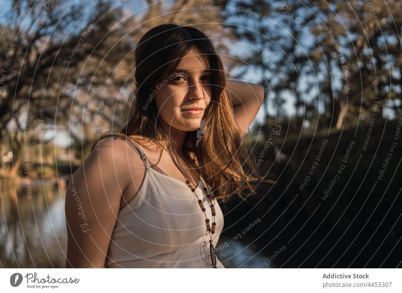 Zärtlicher Teenager berührt Haare im Park am Fluss Haare berühren reflektierend charmant sanft Verlockung angenehm feminin natürlich rein Angebot idyllisch