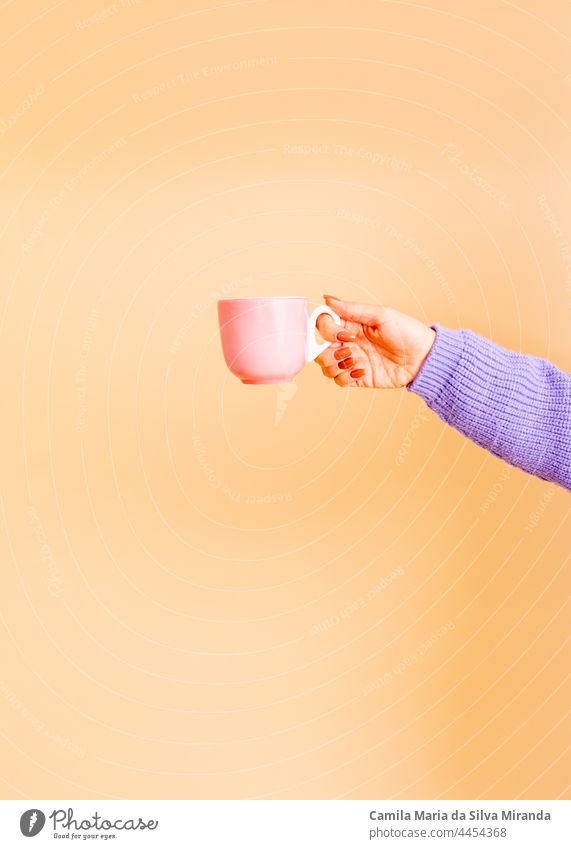 Nahaufnahme von weiblichen Händen, die eine hellrosa Tasse halten. Mädchen mit schönen Nägeln. hält Tasse Tee oder Kaffee. Studio-Foto. Foto zum Zuschneiden. Leere.