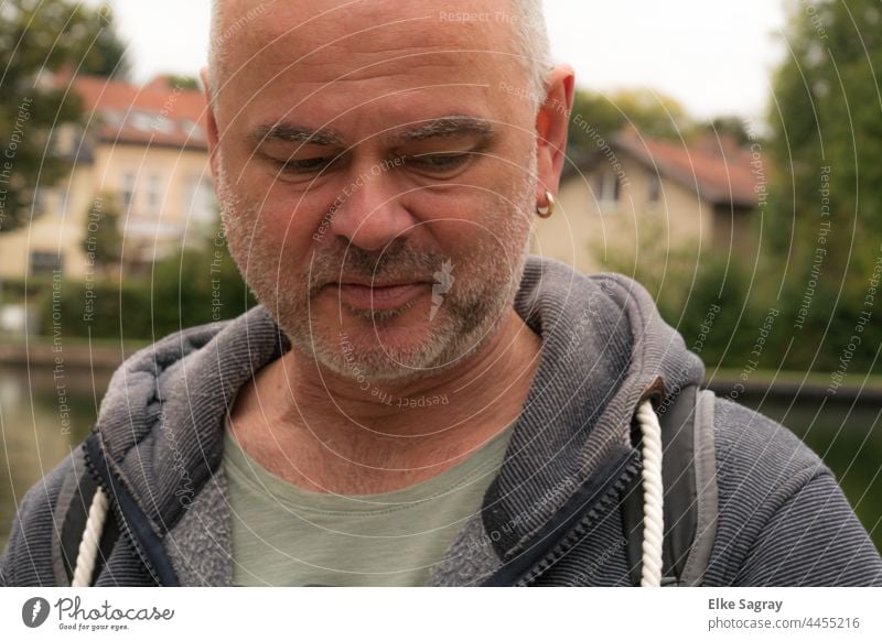 Nachdenklicher junger Mann am Wasser Porträt Gesicht Nahaufnahme maskulin Bart Dreitagebart Blick nach unten Farbfoto Schwache Tiefenschärfe Junger Mann