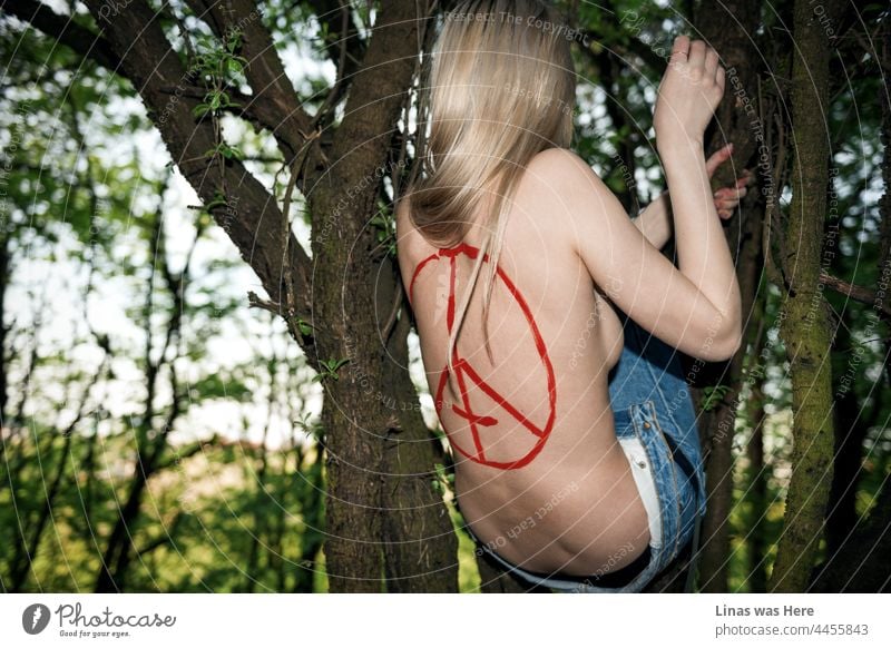 So ist es, wenn man in einem Baum lebt. So wie dieses nackte, wunderschöne blonde Mädchen es tut. Sie klettert auf Äste, nur mit Bluejeans bekleidet und einem roten Teufelszeichen auf ihrem sexy Rücken. Wildes Blut gemischt mit perfektem Sommerwetter in den Wäldern.