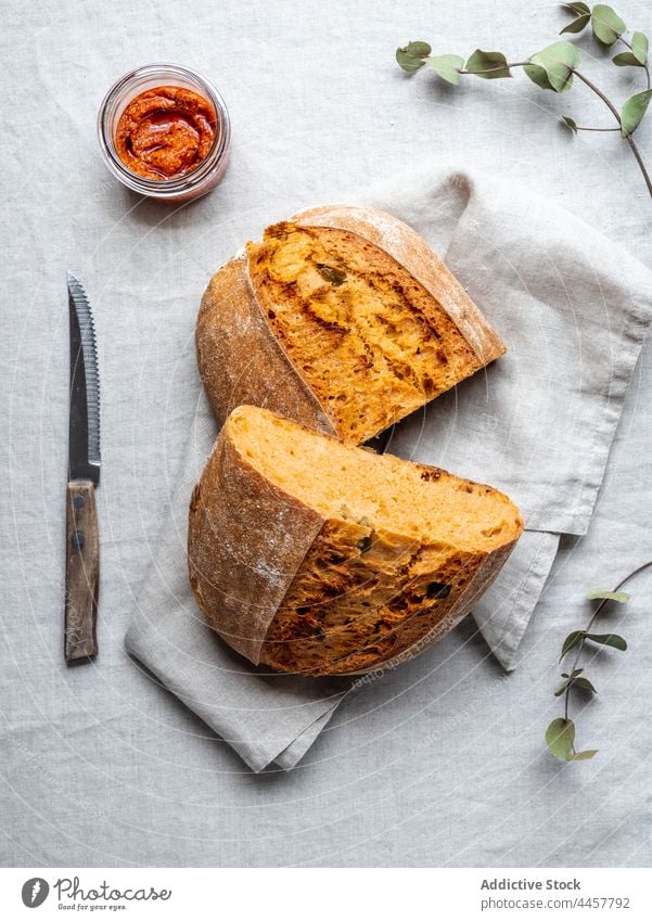 Brot und Pestosauce auf dem Tisch Hälfte Brotlaib Saucen gebacken Layout dienen italienische Küche Tradition lecker Serviette Messer Lebensmittel natürlich