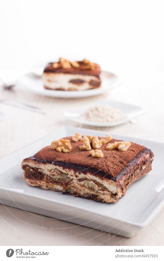 Leckere Tiramisu-Torte auf dem Teller tiramisu Kuchen Dessert Walnussholz Garnierung geschmackvoll selbstgemacht dienen süß Tisch lecker Konditorei Kakao Pulver