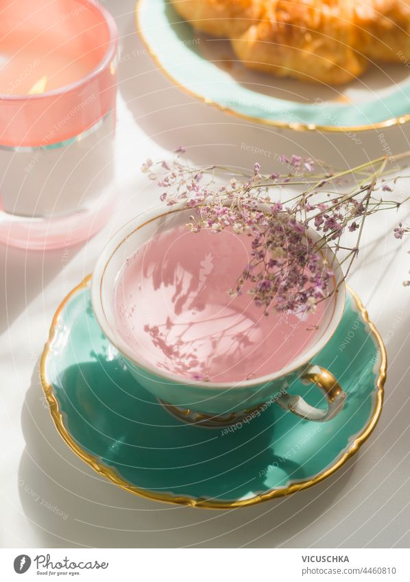 Nahaufnahme von rosa Blumen Tee in türkisfarbenen Teetasse auf sonnigen Frühstückstisch abschließen Tisch Teezeit authentisch Hintergrund Tasse trinken geblümt