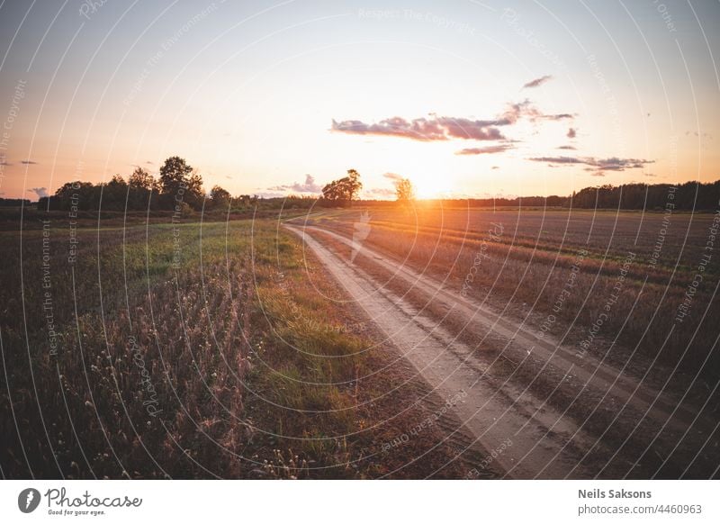 Weitwinkelansicht der Landschaft über Wiese und Straße bei Sonnenuntergang in flacher Agrarlandschaft landwirtschaftlich Ackerbau Herbst Hintergrund schön blau