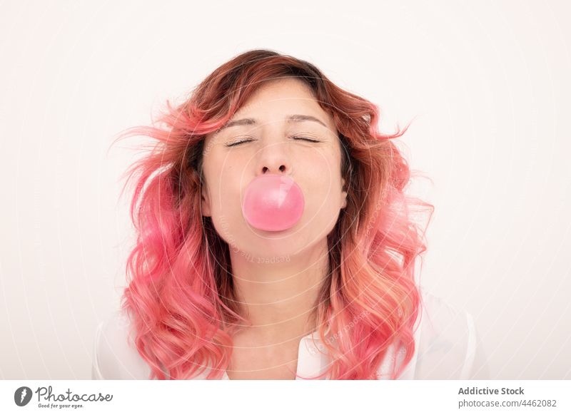 Positive Frau mit rosa Kaugummi Schaumblase Schlag positiv Individualität heiter Freude Zahnfleisch Vorschein Kauen Stil Glück Optimist Licht trendy rosa Haare