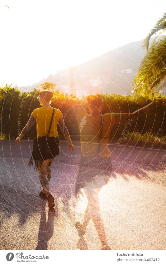 Junge Frau mit Tattoos auf einer Straße im Süden, Doppelbelichtung, Italien Palmen Sonnenlicht Gelb Handtasche Pony Sonnenbrille Sunset freude Jubel Stimmung