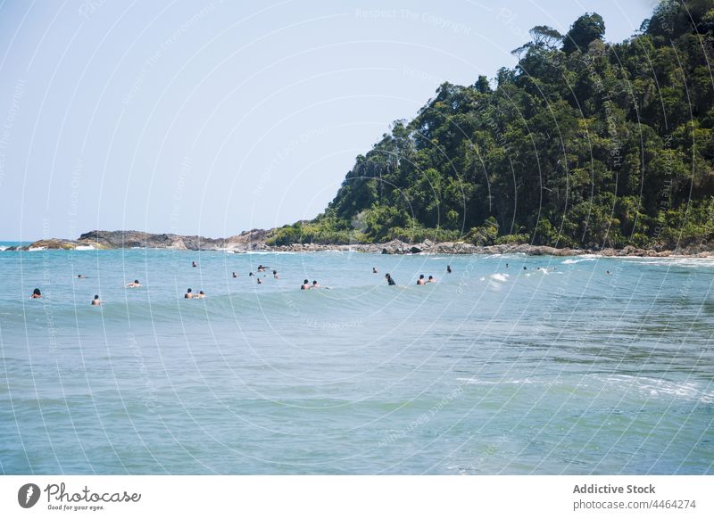 Reisende schwimmen im wellenförmigen Meer gegen einen Berg mit Bäumen Tourist Himmel Berge u. Gebirge Natur Landschaft Hochland Urlaub Umwelt Baum Ökologie