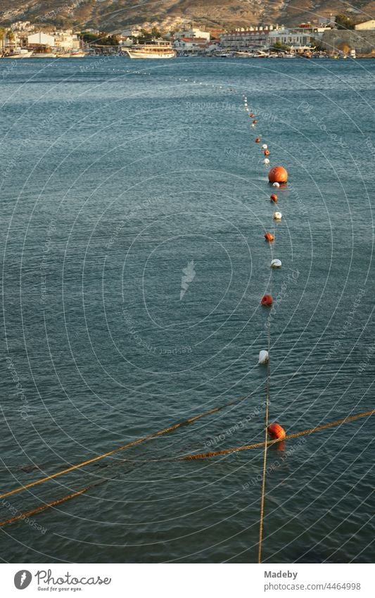 Schwimmer und Bojen kennzeichnen den Schwimmbereich am Hafen and der Bucht von Foca im Sommer im Licht der Abendsonne am Ägäischen Meer in der Provinz Izmir in der Türkei