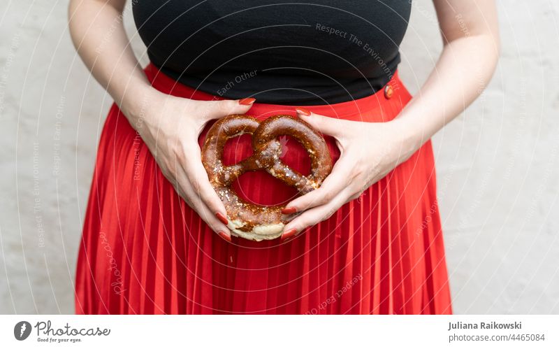 Frau hält eine Bretze Oktoberfest Jahrmarkt Freude Feste & Feiern Essen Gebäck Tag Außenaufnahme Veranstaltung Farbfoto mehrfarbig Glück Tradition Bayern dirndl