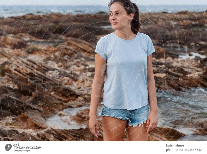 Teenager-Mädchen steht auf Klippe am Meer bei Sonnenuntergang. Shirt Mockup T-Shirt Attrappe blau Kaukasier MEER Felsen Jugendlicher Stein tragend Stehen