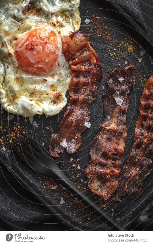 Leckeres Spiegelei und Speckstreifen mit Gewürzen Ei Frühstück gebraten Lebensmittel Ernährung lecker Besteck Tablett Gewebe appetitlich Scheibe natürlich