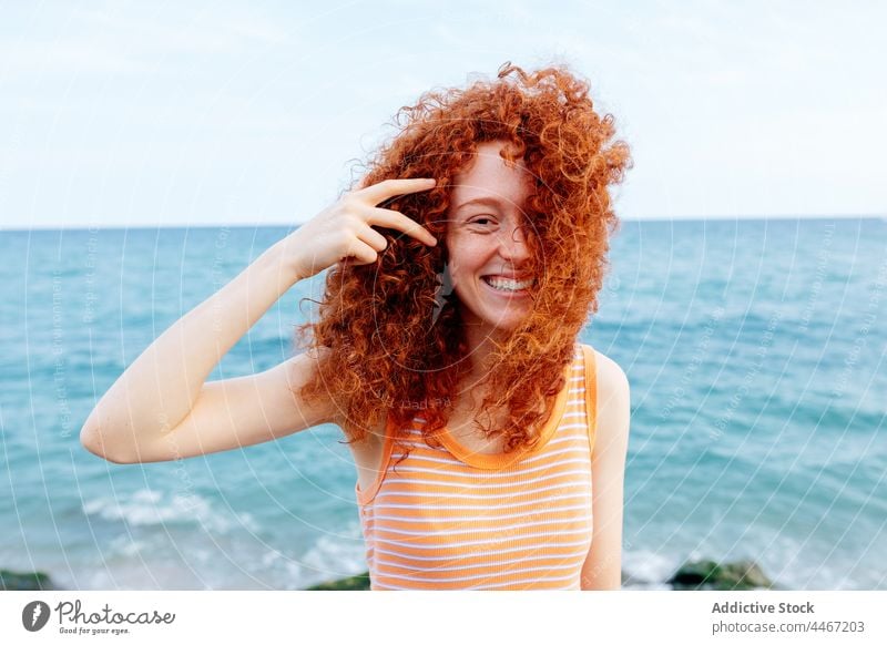 Fröhliche Frau am Meeresufer stehend Glück blau MEER Wind Ufer froh Urlaub Feiertag Freude heiter lange Haare Rotschopf Wasser Natur Optimist Ingwerhaar positiv