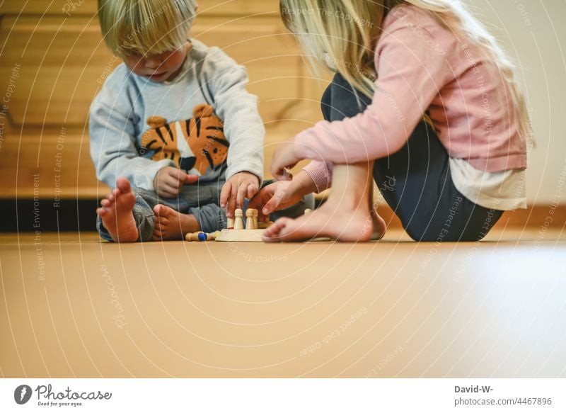 Kinder spielen zusammen ein Gesellschaftsspiel Geschwister Spiel Gesellschaftsspiele gemeinsam beschäftigung geschwisterliebe Spaß konzentriert denken erklären