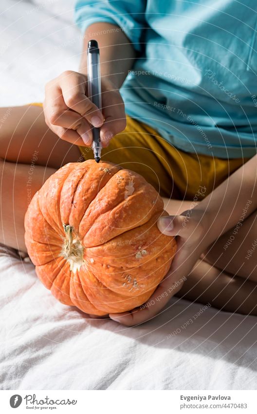 Junge macht Jack-o-Lantern zu Hause. Halloween DIY Konzept. Herstellung Kürbisse Dekor diy Kind Farbe Filzstift Lifestyle fallen Kunst festlich Zeichnung lustig