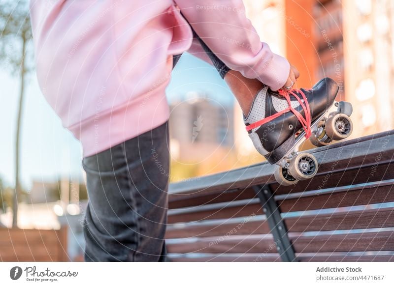 Anonyme Frau beim Anziehen von Rollschuhen im Park Schlittschuh Rolle Bank Spitze aktiv anlehnen Aktivität rosa Hobby Bein Kapuzenpulli Outfit schlank urban