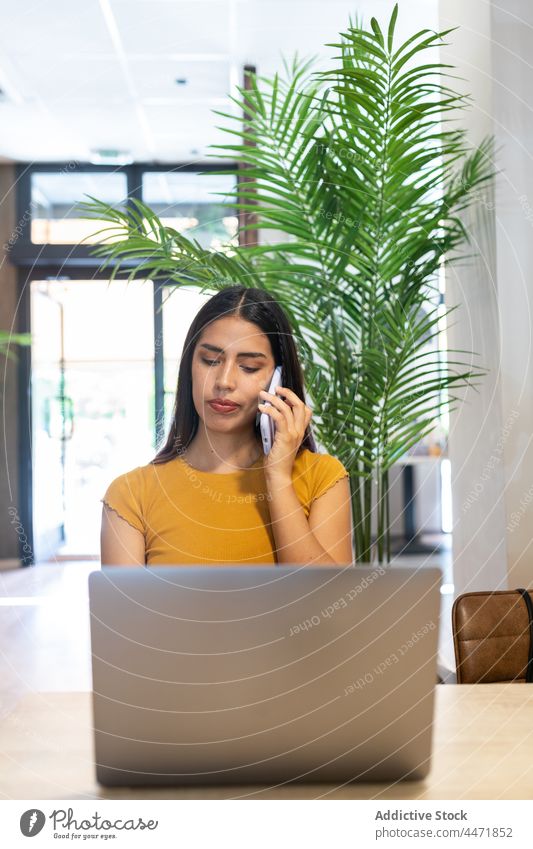 Beschäftigte Frau, die mit ihrem Smartphone spricht und einen Laptop benutzt benutzend abgelegen Tippen Telefonanruf Arbeit zuschauen Projekt freiberuflich