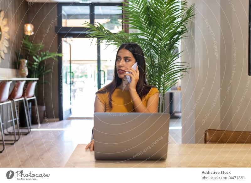 Beschäftigte Frau, die mit ihrem Smartphone spricht und einen Laptop benutzt benutzend abgelegen Tippen Telefonanruf Arbeit zuschauen Projekt freiberuflich