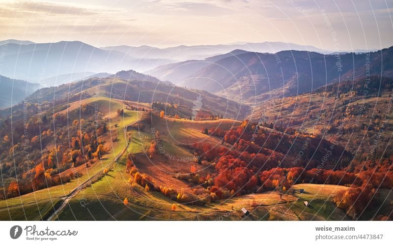 Schöne Berg-Herbstlandschaft mit Wiese und buntem Wald. Rote, gelbe und orangefarbene Bäume an den Hängen. Landschaft Berge fallen farbenfroh Natur Hintergrund