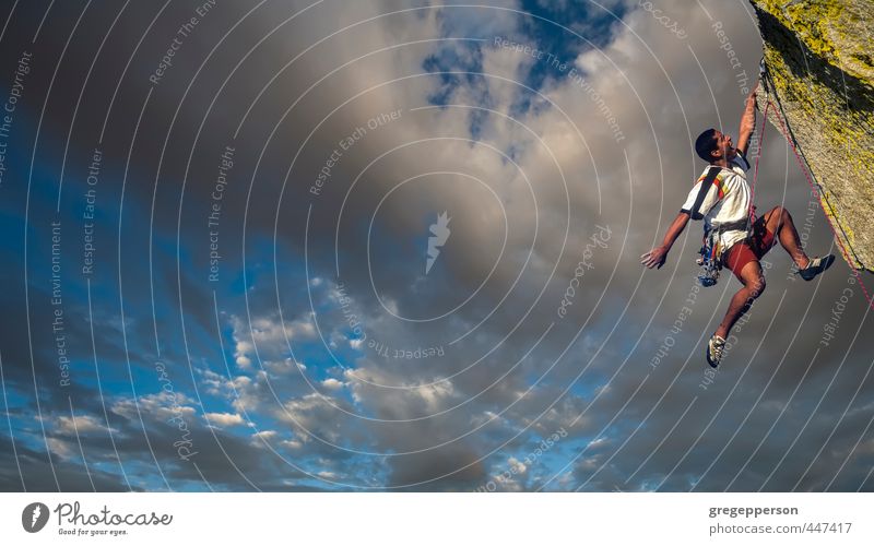 Ethnischer Kletterer, der vom Rand baumelt. Abenteuer Klettern Bergsteigen Erfolg maskulin 1 Mensch 18-30 Jahre Jugendliche Erwachsene Wolken Gipfel