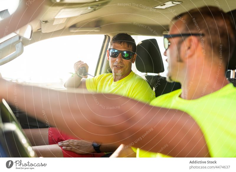 Mann am Steuer mit Kollege im Gespräch über Walkie-Talkie Männer Rettungsschwimmer Laufwerk PKW Arbeit Sicherheit Anschluss Dienst männlich Sonnenbrille Beruf