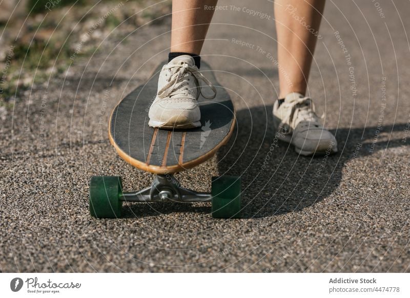 Anonyme Frau fährt Longboard auf einer asphaltierten Straße Mitfahrgelegenheit Aktivität Hobby genießen Freizeit Natur Gleichgewicht wolkig Training Hügel