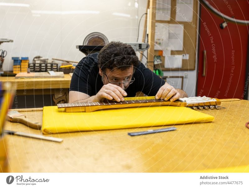 Professioneller Meister misst Gitarrenhals im Studio Kunsthandwerker Instrument Atelier professionell messen Beruf Bünde Werkstatt Basteln Mann Konzentration