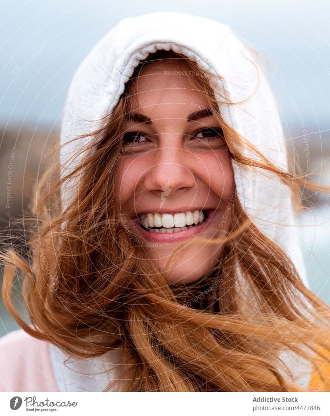 Rothaarige Frau mit Kapuze schaut in die Kamera Ingwer Behaarung heiter Rätsel charmant Vorschein Freude Porträt fliegendes Haar Wind Rotschopf Galicia Spanien