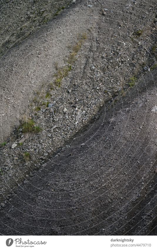 Schutt Kegel aus Boden oder Abraum mit Spuren der Erosion durch schnell fließendes Wasser nach heftigen Regenereignissen Halde Rinnen grafische Wirkung