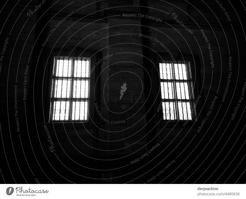 Zwei vergitterte hell erleuchtete Fenster in dunkler Nacht. fenster Fassade architektur Haus Gebäude alt historisch bauwerk brauchtum backstein bauwesen nacht