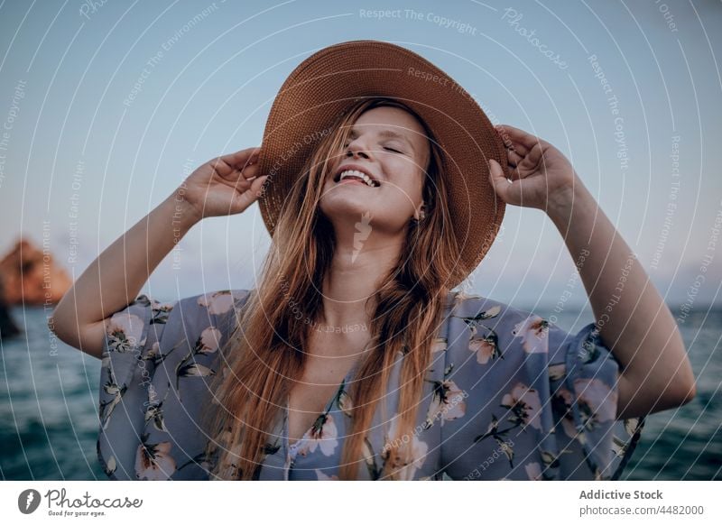 Frau in Kleid und Hut Abend MEER Meeresufer Sonnenuntergang Sommer Freude Glück Küste Strand Stil trendy charmant Seeküste Lächeln Ufer Natur Meereslandschaft