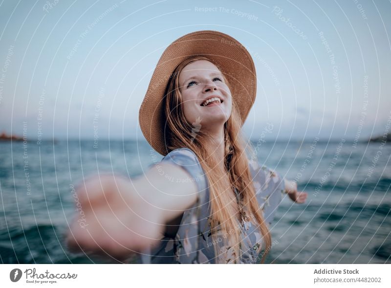 Glückliche Frau am Sandstrand stehend MEER Strand Lächeln Wasser Kleid Sommer Abend jung Natur Küste Ufer Hand Person Meeresufer Harmonie Meeresküste Himmel