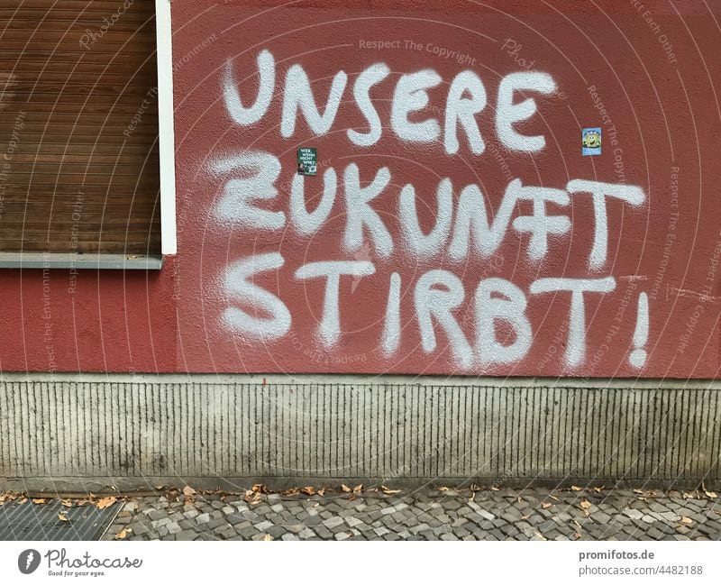 Graffiti auf roter Hauswand mit Fenster: "Unsere Zukunft stirbt!" / Foto: Alexander Hauk Wand silber geschlossen Außenaufnahme Tageslicht Gehweg Bürgersteig