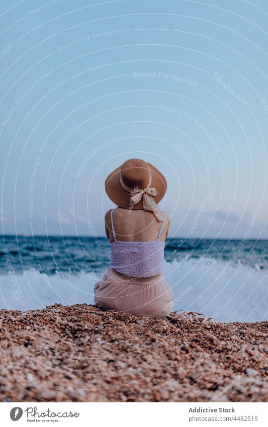 Anonyme Frau mit Hut sitzt am Meer MEER Küste Felsen Sommer Natur Wasser Strand Outfit Sandale felsig Stein sitzen Ufer Umwelt bewundern Rippeln friedlich