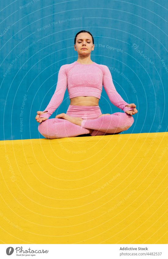 Ruhige Frau sitzt und meditiert Lotus-Pose Windstille meditieren Wellness Harmonie Sportkleidung friedlich üben Zen Yoga sich[Akk] entspannen Gesundheit jung