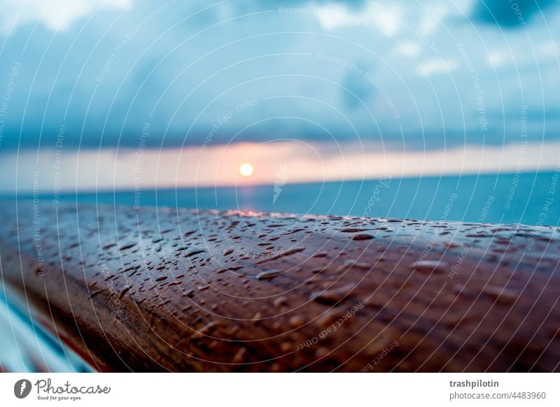 Regentropfen auf der Reling Sonnenaufgang Meer Reeling Tropfen Meereslandschaft Meerwasser Sonnenlicht Wolken rote sonne