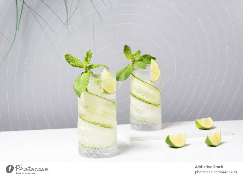 Erfrischender Cocktail mit Limette und Gurke, serviert auf einem weißen Tisch Gin Tonic Kalk Salatgurke Zitrusfrüchte Alkohol Minze Getränk Frucht cool