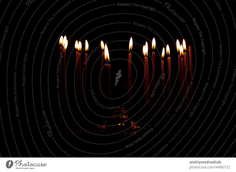 Nahaufnahme einer Menge brennender Kerzen isoliert auf schwarzem Hintergrund. Kerzenschein Flamme Feuer Nacht glühen Kirche Religion Brandwunde Weihnachten