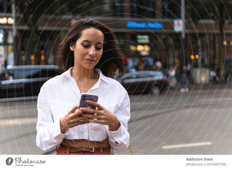 Stilvolle Frau mit Mobiltelefon Smartphone Straße Großstadt PKW Gebäude urban trendy benutzend Gerät Mobile online Telefon selbstbewusst Apparatur Browsen