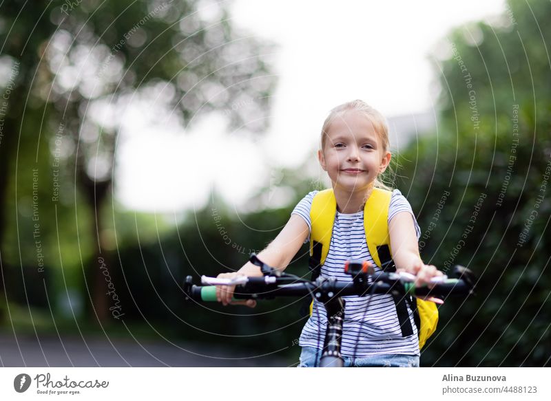 Blondes Mädchen mit gelbem Rucksack, das nach der Covid-19-Quarantäne und der Abriegelung mit dem Fahrrad zur Schule zurückkehrt. zurück zur Schule Kind Bildung