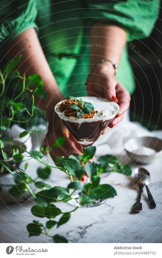 Crop-Frau serviert Mousse im Glas auf dem Tisch Schokolade Kokosnuss dienen Murmel Dessert süß frisch geschmackvoll lecker natürlich Minze Blatt grün