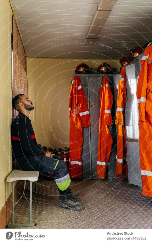 Erschöpfter Feuerwehrmann auf der Feuerwache Station Uniform Spind müde professionell Beruf Mitarbeiter Mann Schutzhelm männlich jung Sicherheit Held ernst