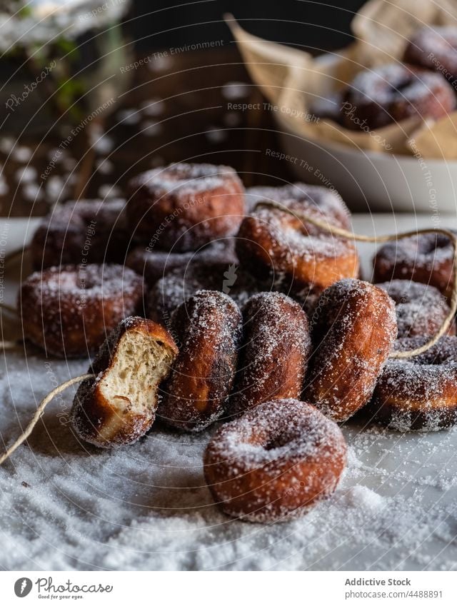 Krapfen in Puderzucker auf dem Tisch Fritter süß Zucker Pulver Gebäck Dessert Doughnut Leckerbissen lecker geschmackvoll Lebensmittel appetitlich gebacken