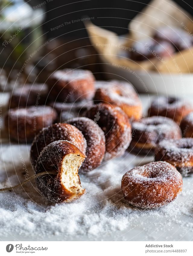 Krapfen in Puderzucker auf dem Tisch Fritter süß Zucker Pulver Gebäck Dessert Doughnut Leckerbissen lecker geschmackvoll Lebensmittel appetitlich gebacken