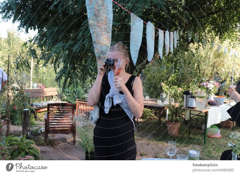 Jugendliche mit Kamera und Sektglas auf einem Gartenfest Mädchen junge Frau feiern fotografieren kamera Fotokamera Fotografie Junge Frau Fotografin Fest Partie