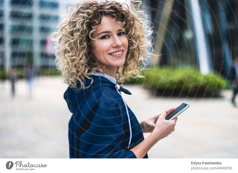 Junge Frau benutzt ein Mobiltelefon in der Stadt Warschau Tag Spaß Kräusel Frisur Sommer Fröhlichkeit im Freien Tourist Schönheit Lächeln heiter echte Menschen