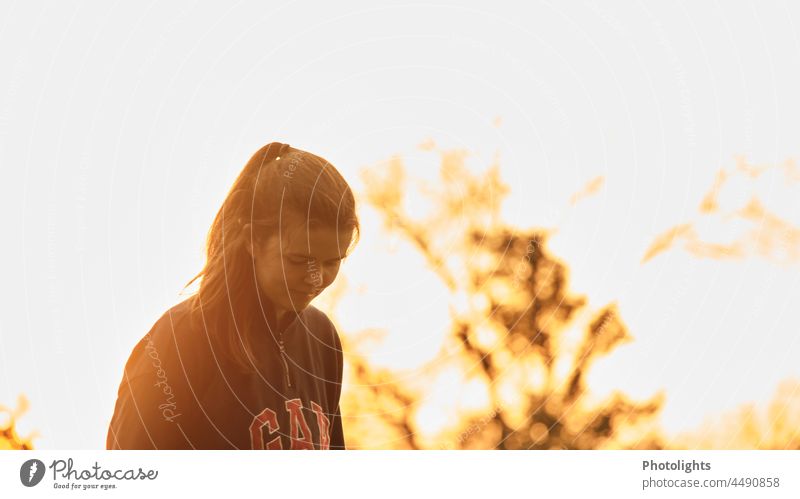 Junge Frau mit Pferdeschwanz bei Sonnenuntergang in warmen Farben Dämmerung Außenaufnahme Farbfoto Zufriedenheit Leben Idylle Interesse Neugier schön träumen