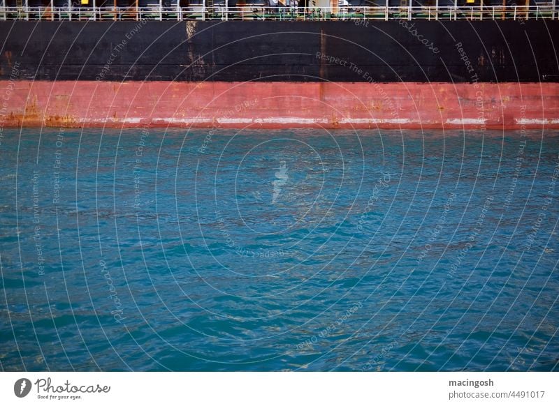 Schiffswand und Wasseröberfläche im Hafen schwarz rot blau Frachtschiff Anlegeplatz ankern Entladen Beladen Schifffahrt Logistik Warentransport Globalisierung